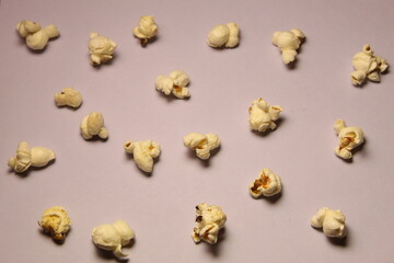 Popcorn kernels spread  on light color background surface.