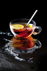 cup of tea with lemon on mirror with reflection and black background