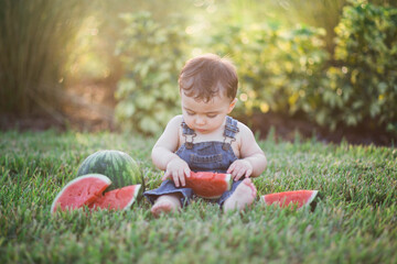 little boy eating watermelon in the backyard 