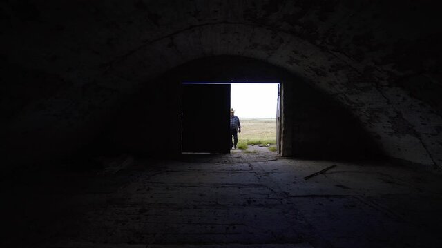 Desperate farmer near an empty barn. World economic crisis. The man went bankrupt due to the crisis. A ruined ranch without cows, pigs, sheep, animals. Empty stable, storage. Unemployed farmer.