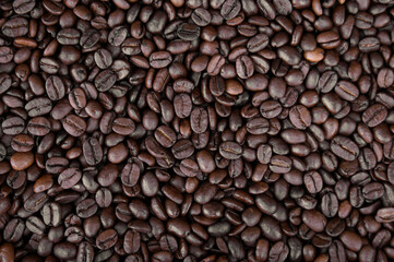 Mixture of different kinds of fresh roasted brown coffee beans in dark tones