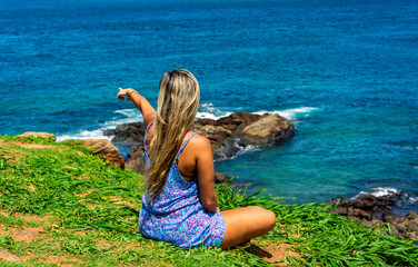 Young woman sitting on the beach looking at the sea and sky