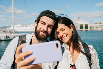Couple smiling as they make a selfie in front of the sea