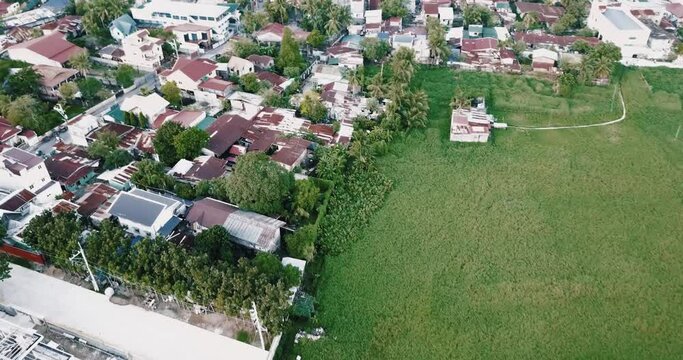 Faded aerial flyover dolly in birds eye view shot of houses, neighbourhood, streets, roads and traffic of cars, bikes and tricycles of a village, town, regional city in philippines south east asia