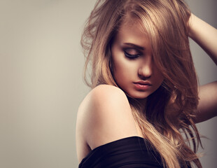 Beautiful natural makeup woman with long blond hair style in black dress, pink lipstick looking...