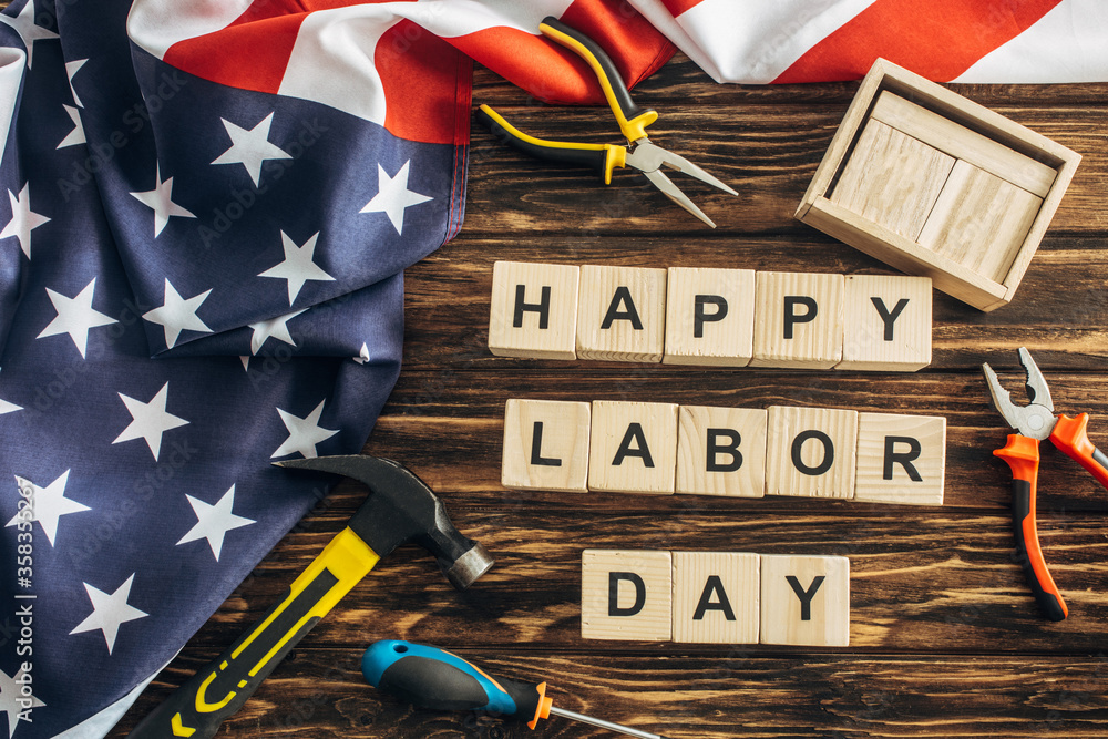 Sticker top view of american flag and instruments near happy labor day lettering on wooden surface