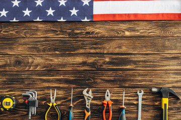 top view of metallic tools and american flag on wooden surface, labor day concept