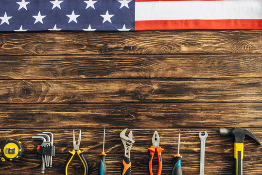 top view of metallic tools and american flag on wooden surface, labor day concept