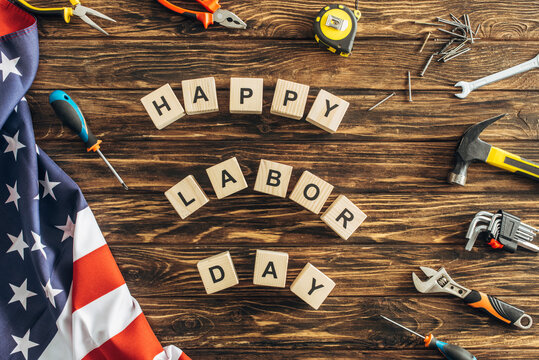 top view of tools and american flag near cubes with happy labor day lettering on wooden surface