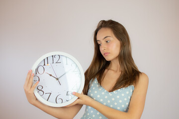 Pretty young girl in dress looking at a big clock
