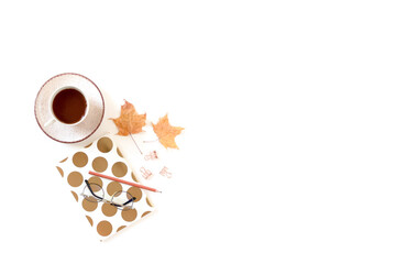 White desk with mug of coffee, notebook, glasses, dried maple leaves. Autumn composition with copy space.