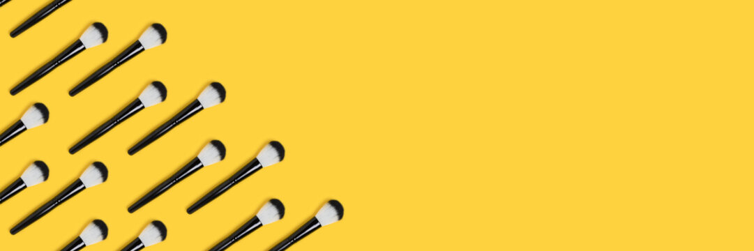 Banner with frame made of makeup brushes pattern on a yellow background. Beauty concept.