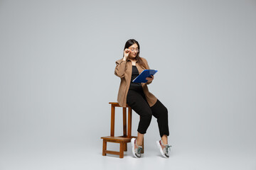 Obraz premium Fashionable, stylish. Young woman in casual wear on gray background. Bodypositive character, feminism, loving herself, beauty concept. Plus size businesswoman during paperwork. Inclusion, diversity.