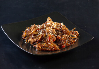 dark buckwheat spicy vermicelli in a dark plate on a dark background