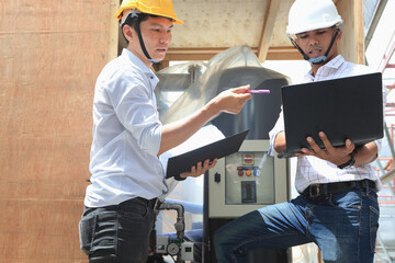 Two engineers are inspecting the machines in the container to make sure they meet the...