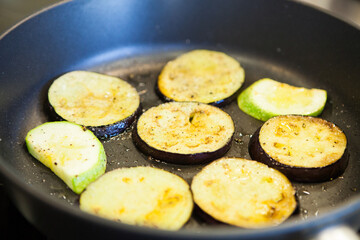 Sliced eggplant and zucchini fried in a pan