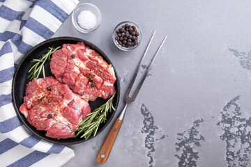 Pork chop meat on a frying pan ready to cook. Top view, text space