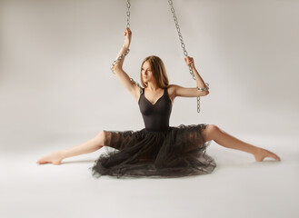 slender girl dancing with a large chain in an incredible ballerina pose
