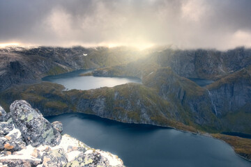 Landscape of harsh Norway, Lofoten Islands. Storm clouds and sunlight over lakes and mountains. Trekking to Munkan Mountain