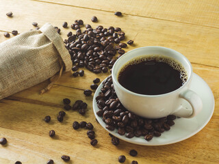 Roasted coffee beans with a cup on wooden background.