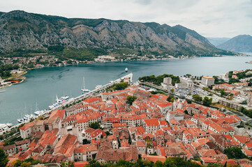Naklejka na ściany i meble Landscape in Montenegro. .Bird's eye view of Boko-Kotor Bay. In the photo - old masonry buildings, cherished roofs, sharp roof spiers against the backdrop of green mountains 