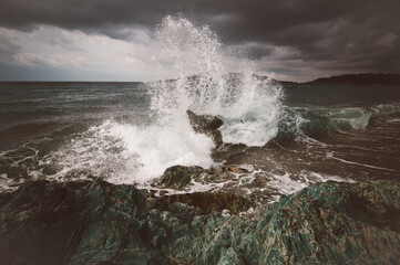 Storm in the Adriatic Sea. A large wave breaks on emerald stones into many small splashes