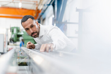 Businessman examining metal rod in factory hall