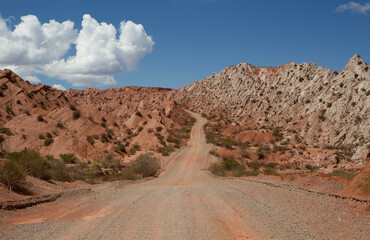 Traveling along the dirt road across the desert and red hills.
