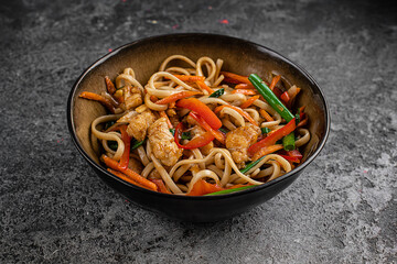 Chicken stir fry with vegetables soy sause and sesame in the wok. Traditional asian food. Top view wiht copy space on stone table.