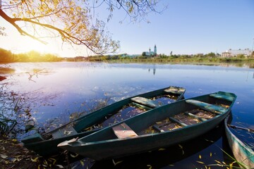 old shabby worn green wooden boats enjoy summer sunrise at river bank in shade of willow tree, rural village seasonal ecotourism concept, free space background image