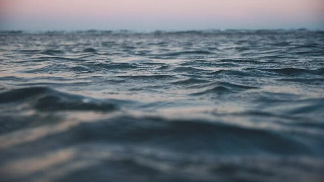 Sea wave in twilight evening close up, low angle view, sunrsie shot, Disturbed dark blue ocean water. Slow motion