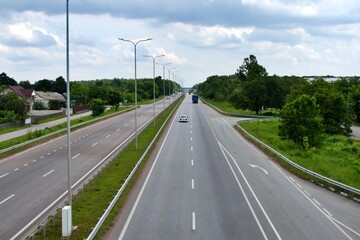 highway going beyond the horizon  with vehicles through the green zone with blurred focus in the background