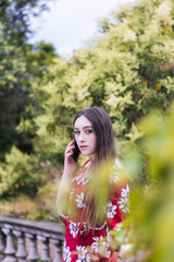 Attractive young woman with red dress making a call outdoor