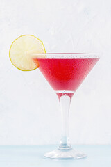 Glass of cosmopolitan cocktail decorated with lime