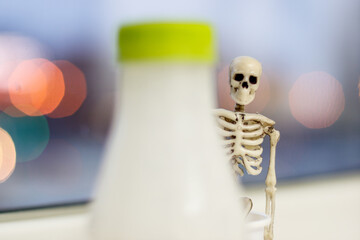 the skeleton peeks out from behind a bottle of milk
