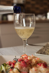 Beautiful glass transparent glasses with champagne and white square plates with food stand on a light wooden table
