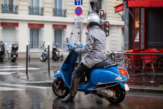 Image of man riding a motorcycle during a rainy day, Paris, France.