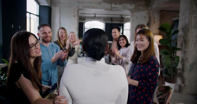 Rear view multiethnic team is clapping to celebrate successful African leader business woman at loft office slow motion.