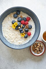 Obraz na płótnie Canvas Overnight oatmeal porridge with fresh berries and edible flowers. Top view