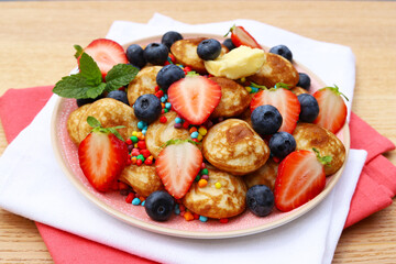 Little pancakes called poffertjes with strawberries, blueberries and colourful candies. 