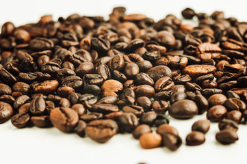 roasted coffee beans are in pile isolated on white,can be used as background or texture. Roasted coffee beans using special technique in which sugars, starches and fats are emulsified into coffee oil