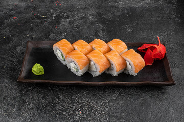 Beautiful Philadelphia Sushi Rolls Set with Salmon and Cream Cheese and Cuccumber on Black Slate Plate Close Up. Uramaki, Nori Maki or Futomaki Sushi with Trout Fillets, Soy Sauce and Wasabi