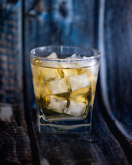 A full glass of whiskey with ice. Serious male drink. Adhesive tape in a glass on a blue background. Alcoholic beverage at the bar.