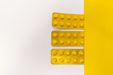 Tablets in packaging on white and yellow background.