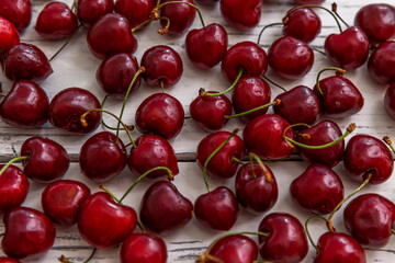 Scattered berries of ripe cherries on a light wooden background. Top view. Seasonal Vitamins.