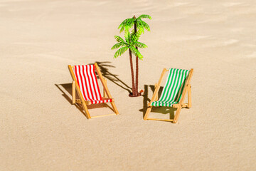 Aerial view of two deck chair, sunbed, lounge, palm tree on sandy beach. Summer and travel concept. Minimalism
