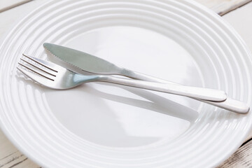 Empty white plate with appliances on a numbed table. Top view.