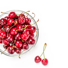 Obraz na płótnie Canvas Glass bowl of fresh red cherries and two berries near bowl on white background