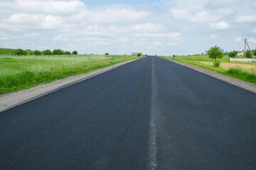 Fototapeta na wymiar New black asphalt. There is no road marking. Reconstruction of the road in Ukraine on a hot day. Copy space.