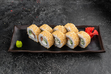 Uramaki Sushi roll with tuna, cheese, avocado, chuka salad, seaweed and sesame isolated on black background with reflection